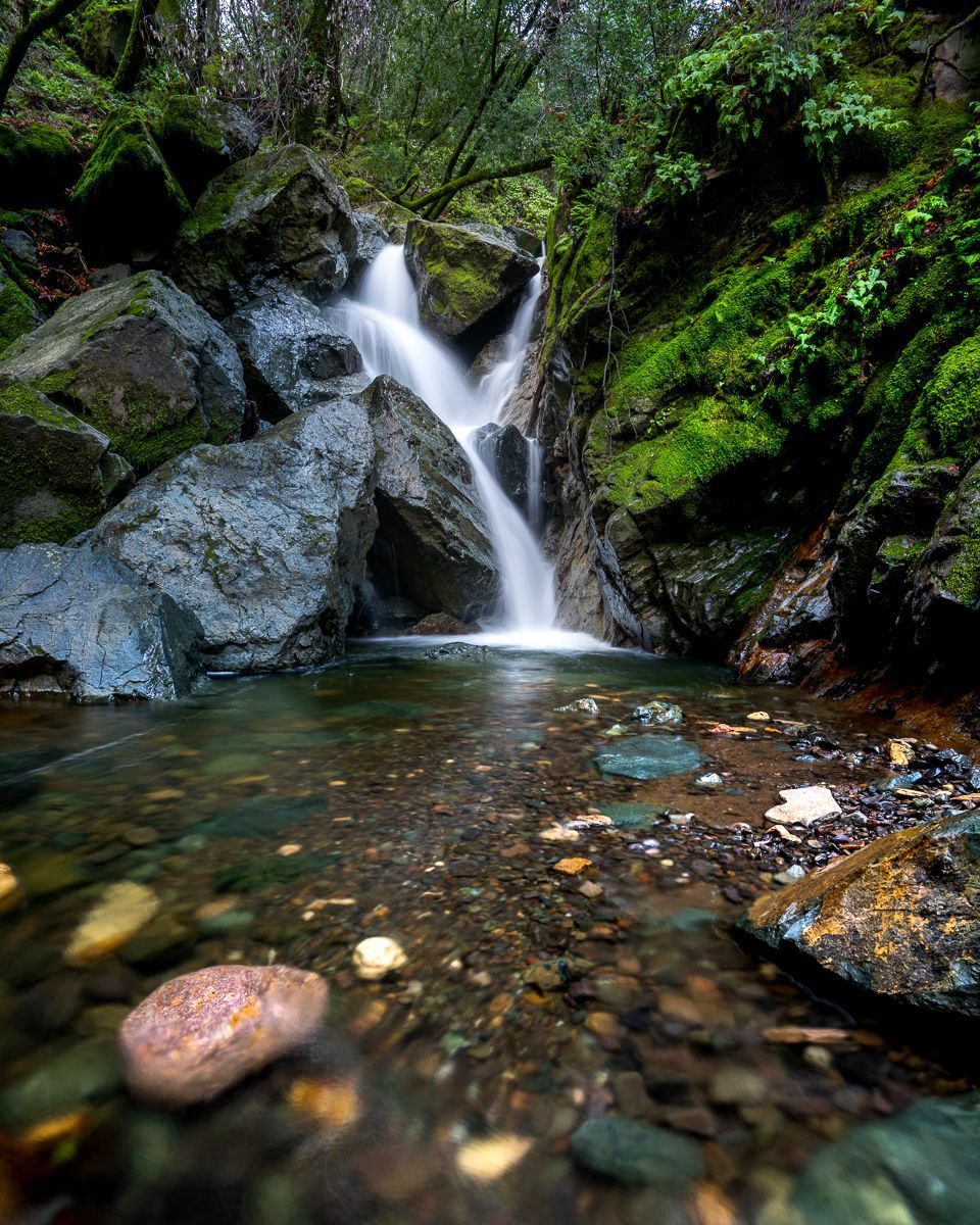 a small waterfall in the middle of a forest surrounded by rocks and moss . Sonoma Creek Falls, Sugarload Ridge State Park, Talking Excitingly, Brad Burgess Photography