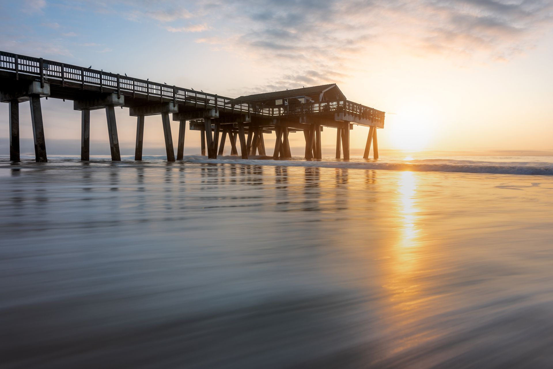 a pier on a beach at sunrise with the sun reflected in the streaking water. Tybee Island Pier, Georgia's Gold Coast, Tybee Island, Brad Burgess Photography, Talking Excitingly