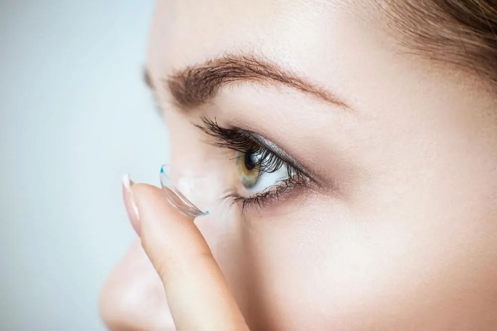 A Woman is Putting a Contact Lens in Her Eye — Michael Chu Optometrist in Cairns North, QLD