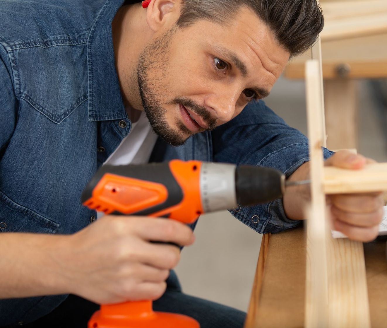 Un uomo sta usando un trapano su un pezzo di legno.