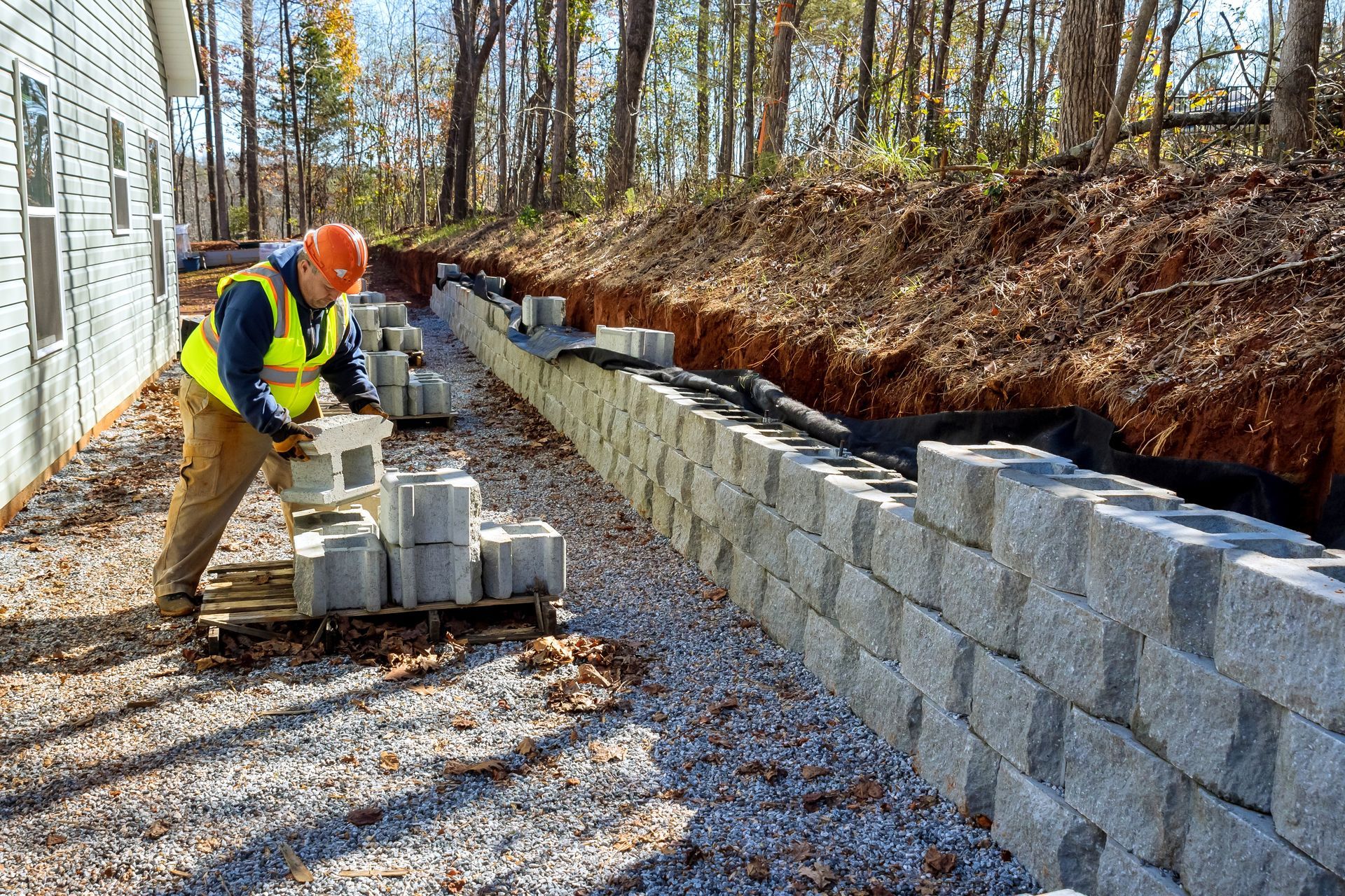 A construction worker is laying bricks on a retaining wall.
