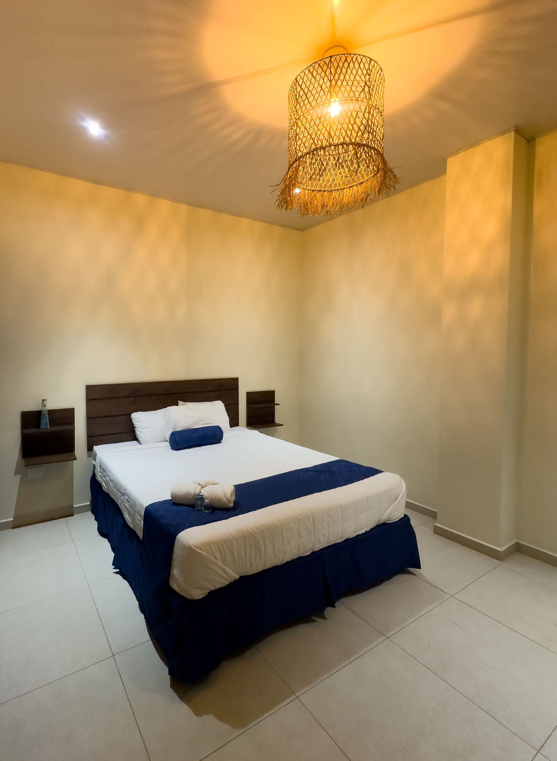 Dormitorio con cama, cabecero de madera, mesitas de noche y lámpara decorativa.