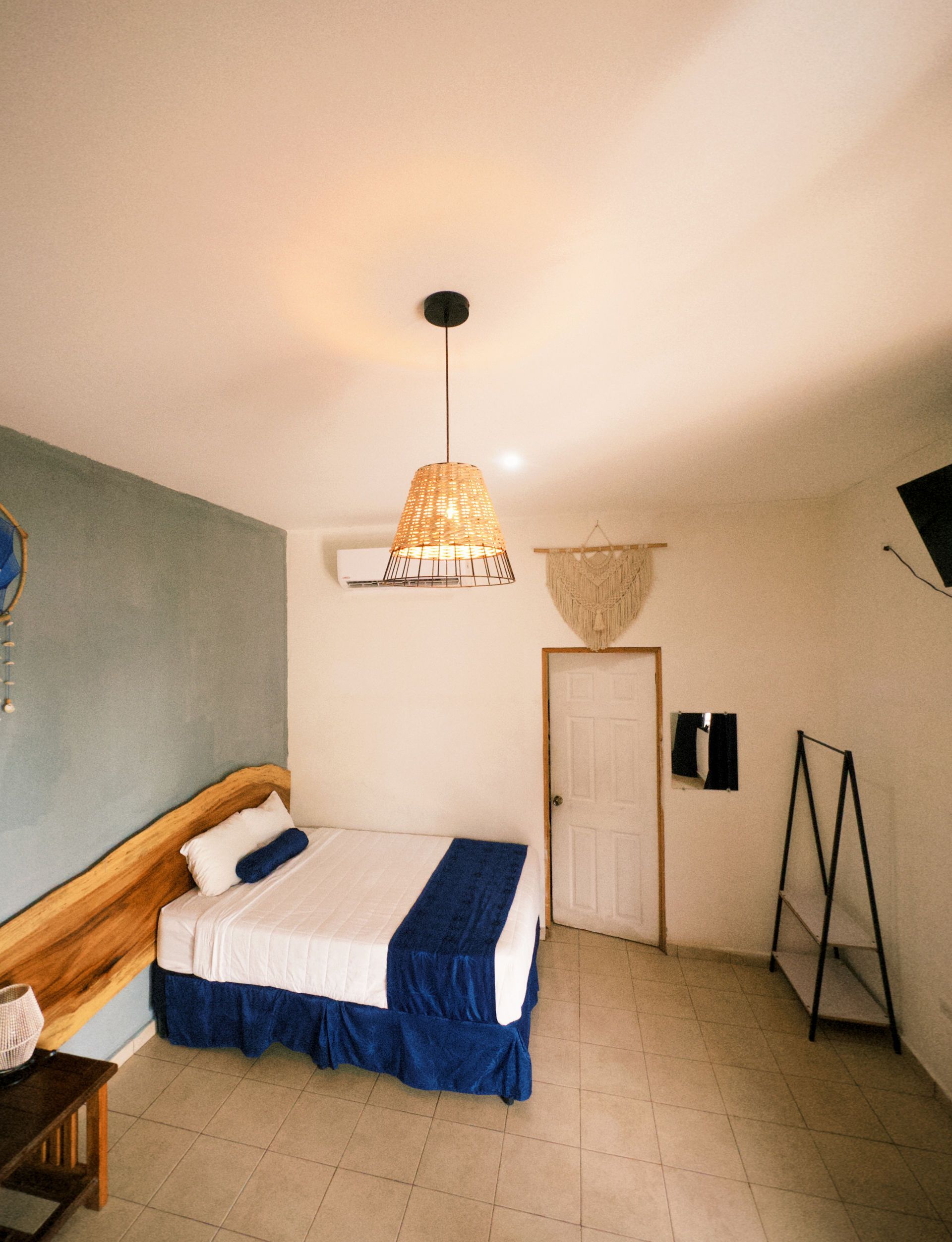 Dormitorio con cama, mesita de noche y lámpara colgante.