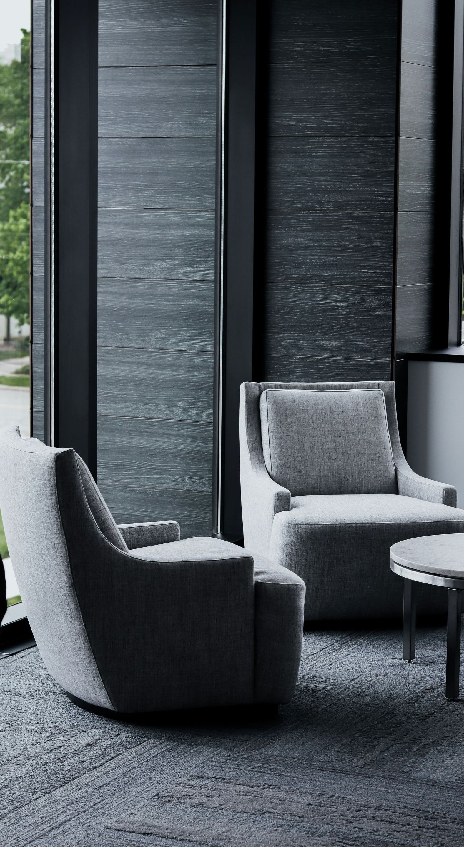 A living room with two chairs and a table in front of a window.