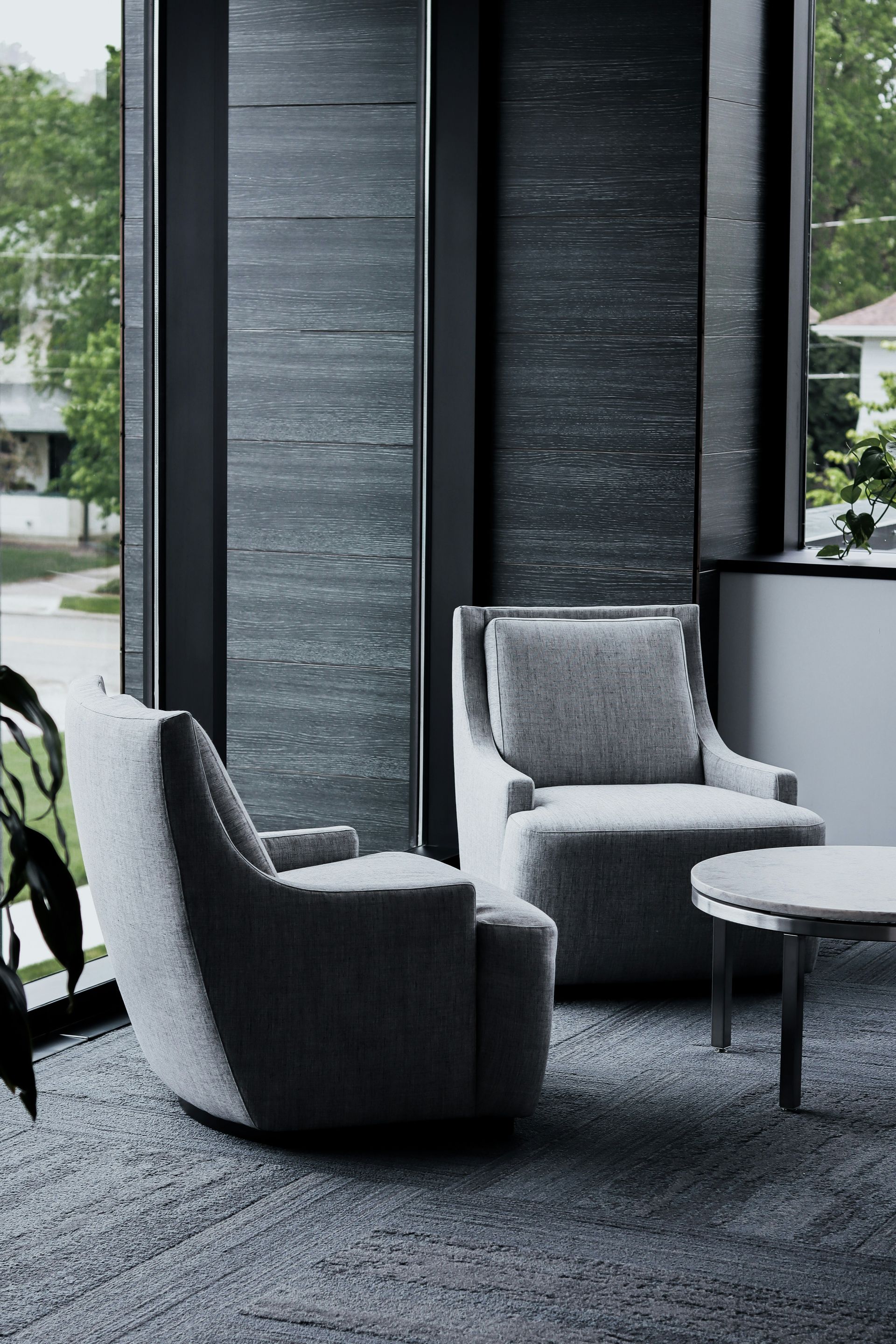 An office lobby with two chairs and a table in front of a window.