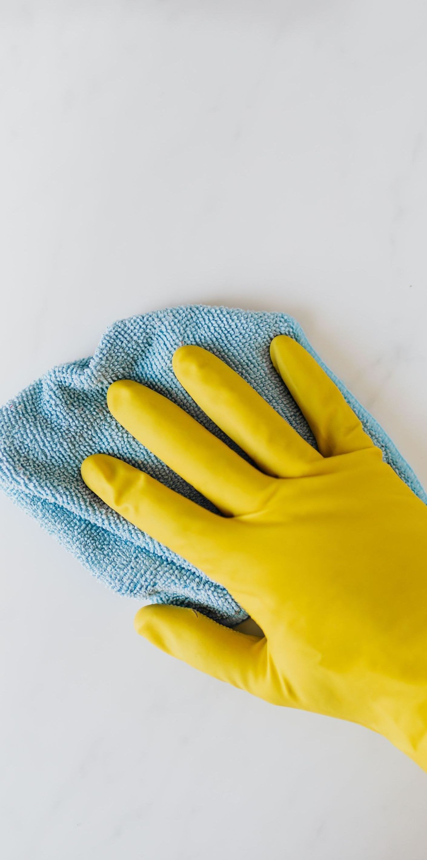 yellow gloves cleaning a surface