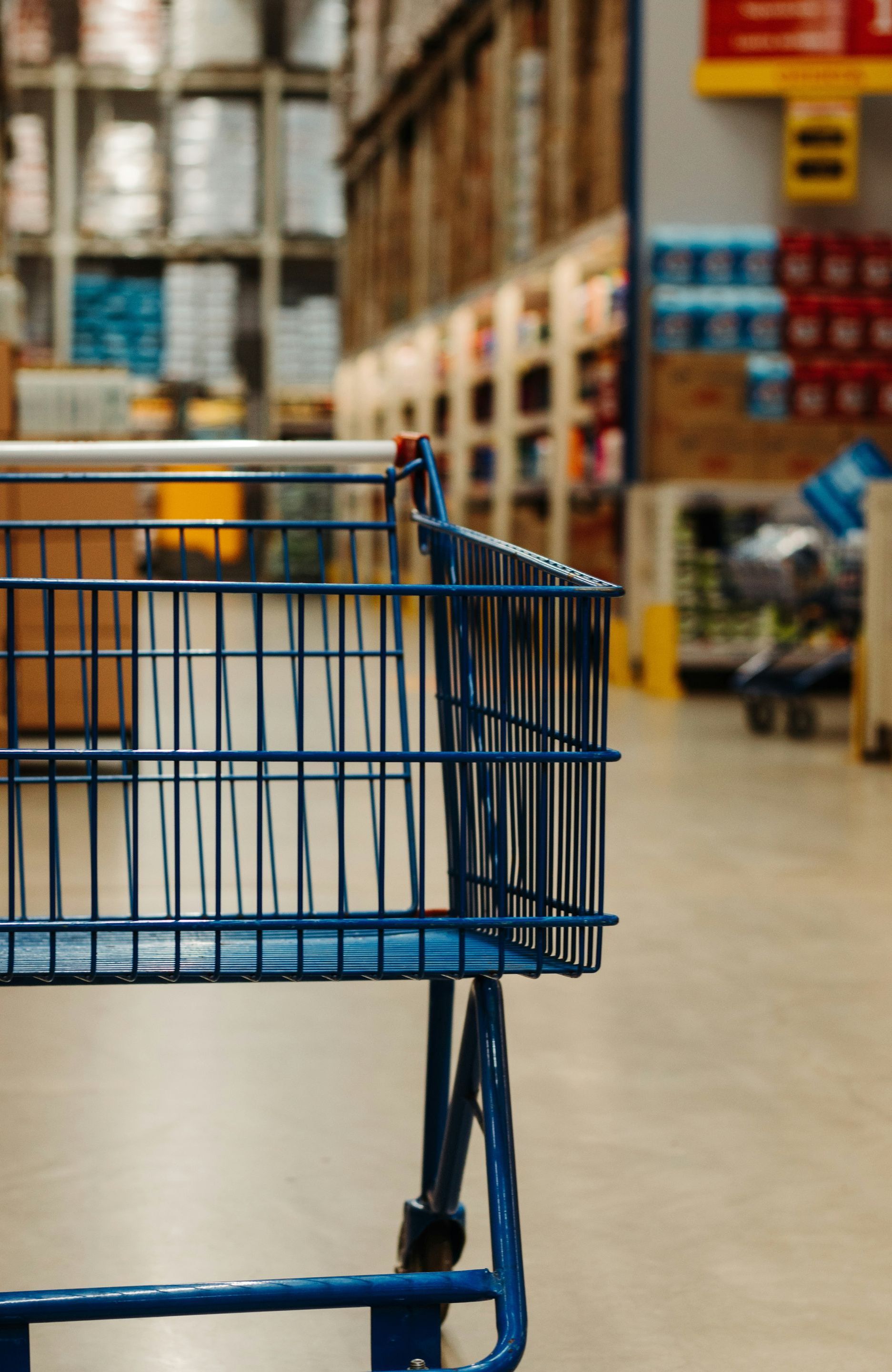 A blue shopping cart is sitting in a warehouse.