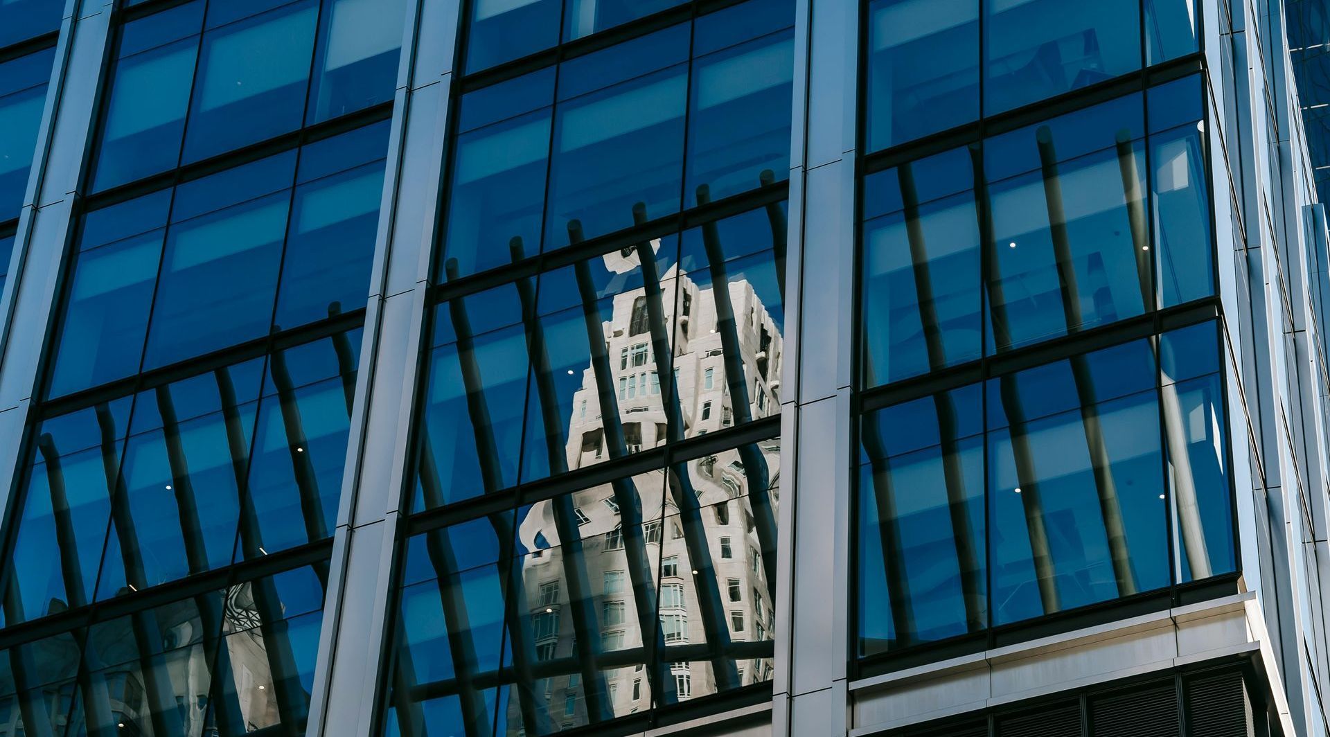 A building with a lot of windows and a reflection of a building in the windows.
