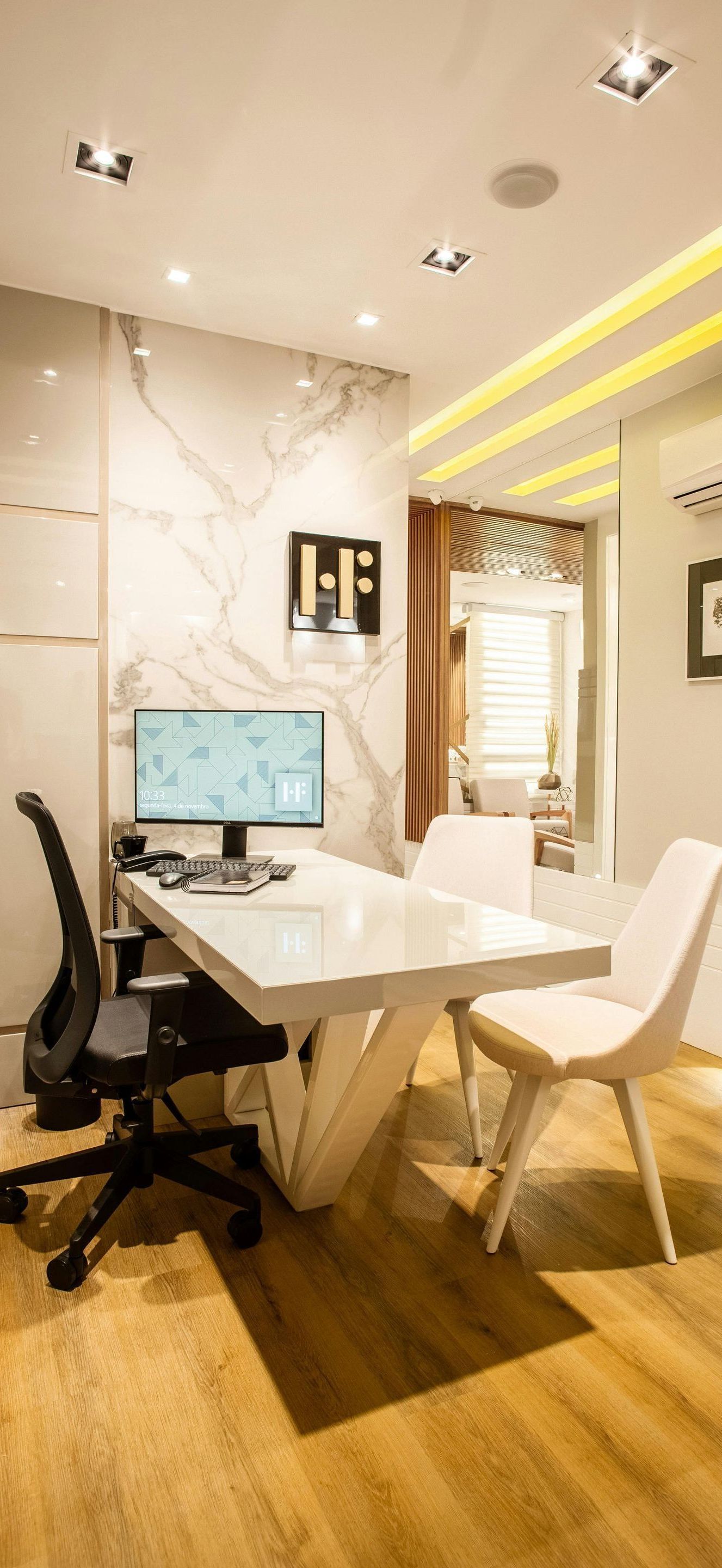 A room with a desk and chairs and a computer on it.