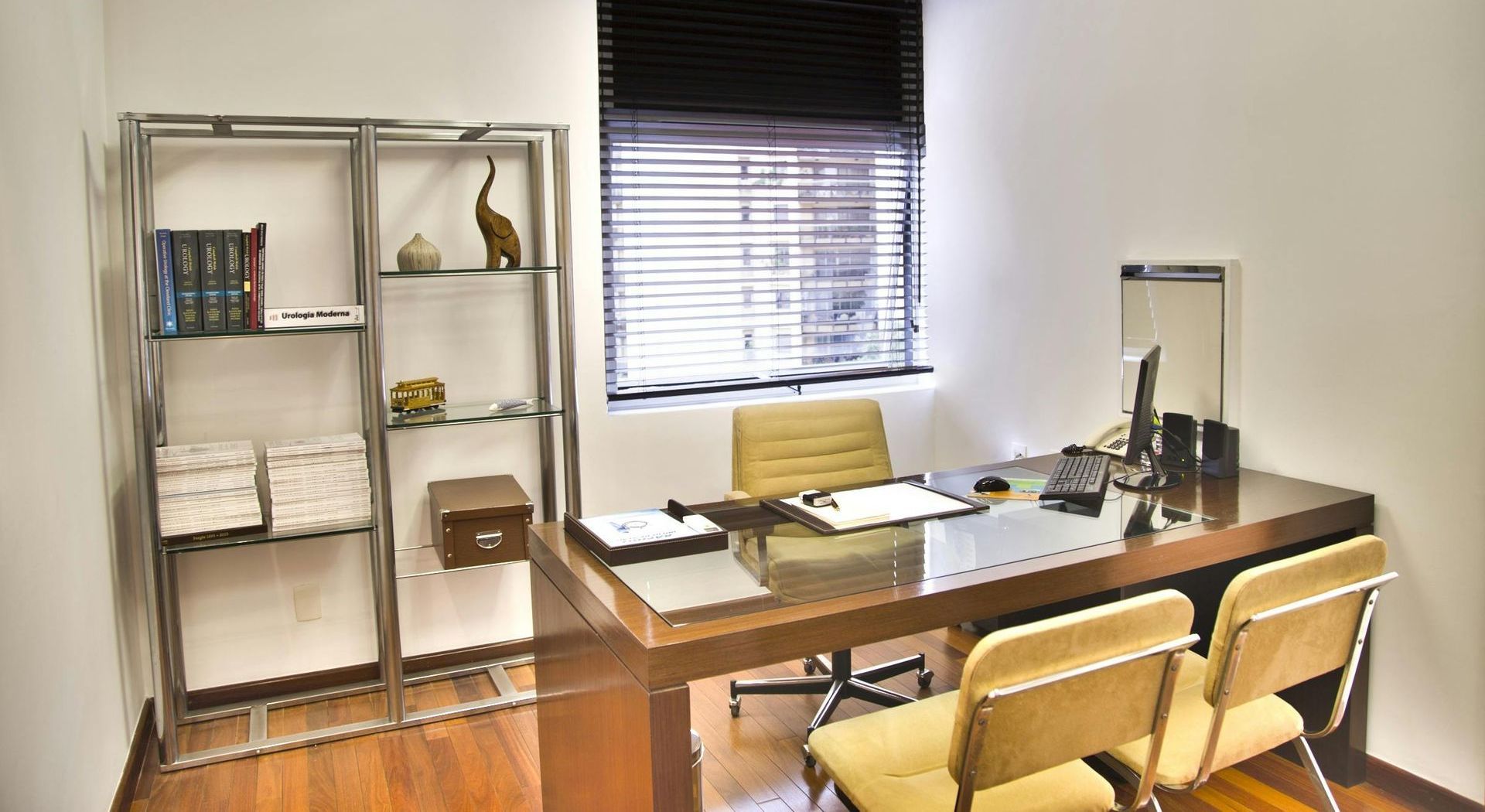 A small office with a desk and chairs and a window