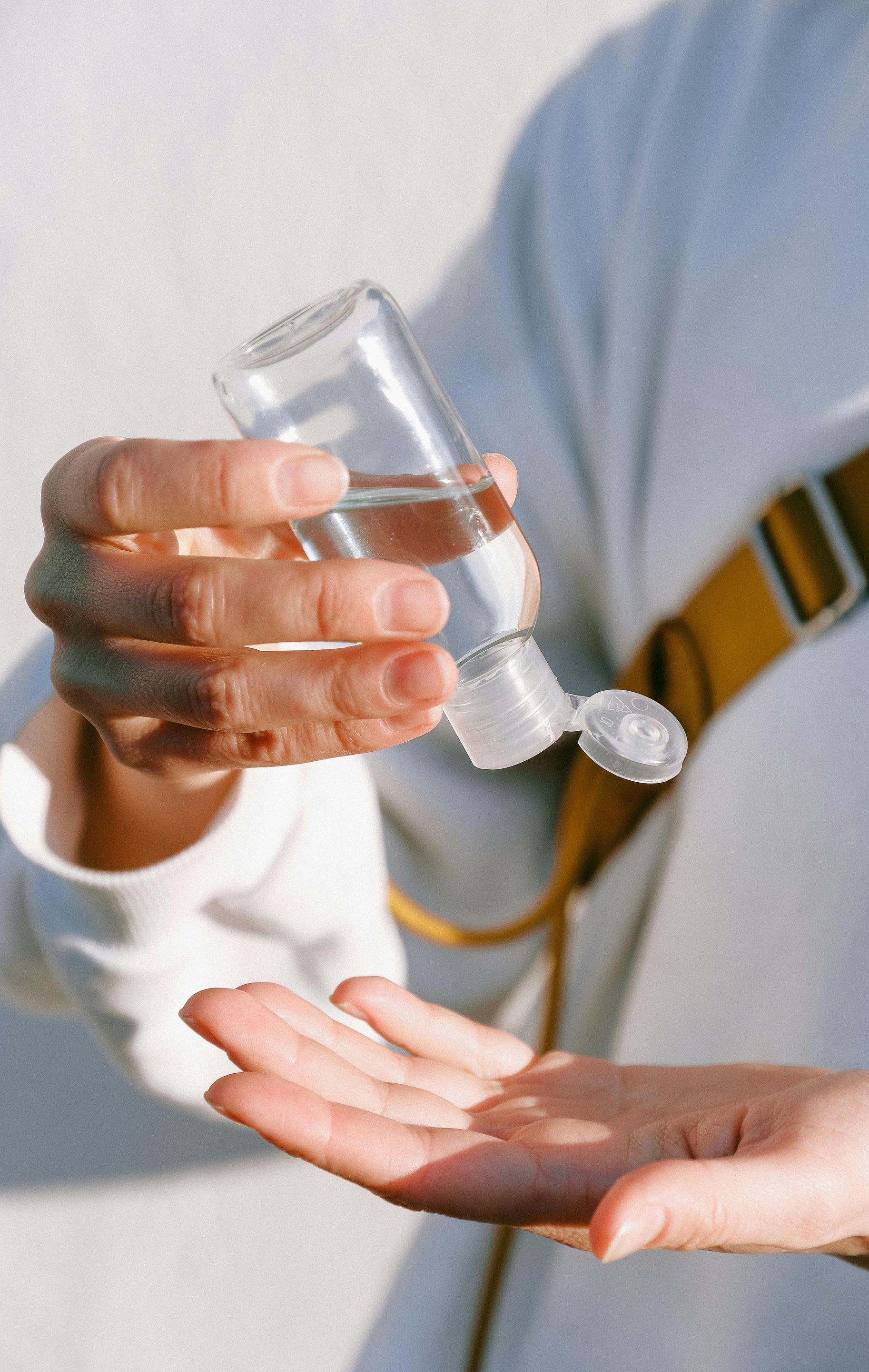 A person is holding a bottle of hand sanitizer in their hand.