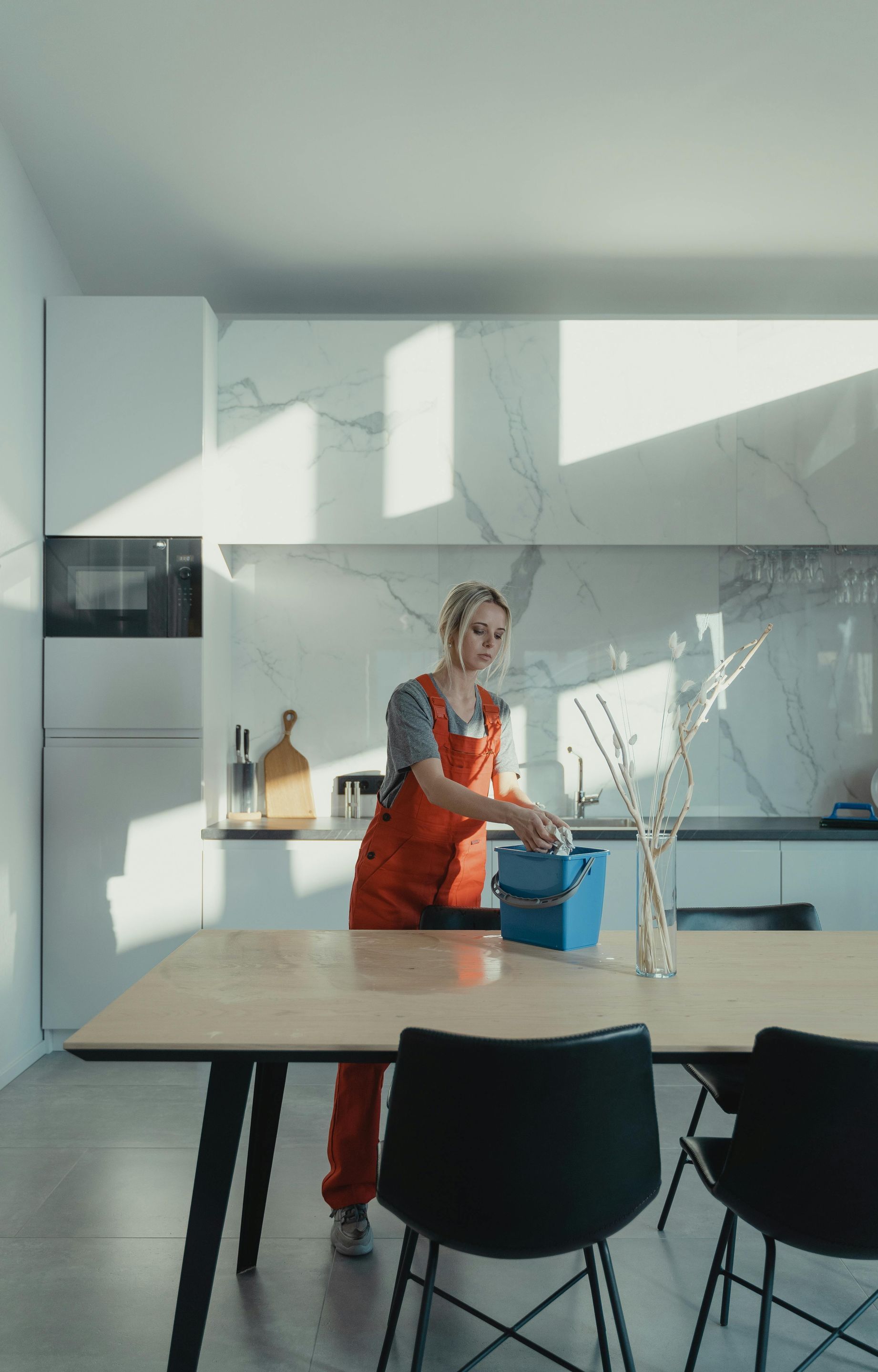 A woman is cleaning a table in a kitchen.