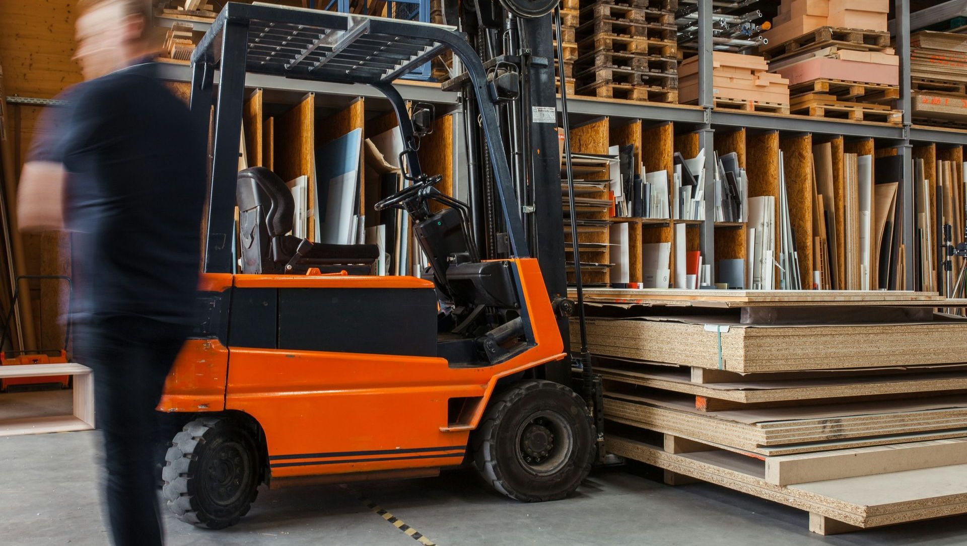 A man is standing next to a forklift in a warehouse.