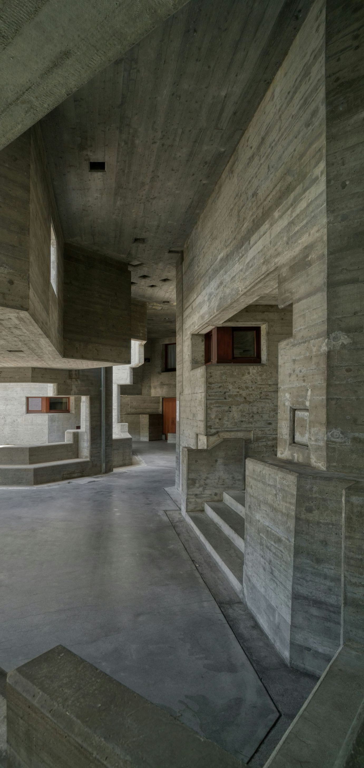 A long hallway in a building with concrete walls and stairs.