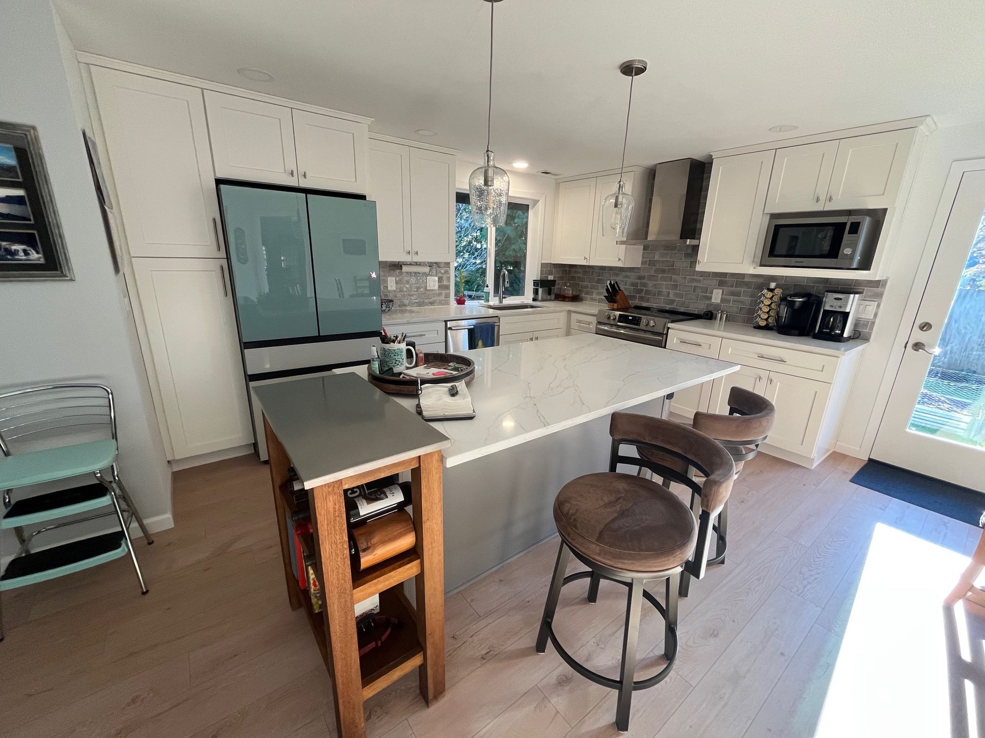 Beautiful modern kitchen featuring sleek white cabinets, state of the art fridge, granite top island, new floors.