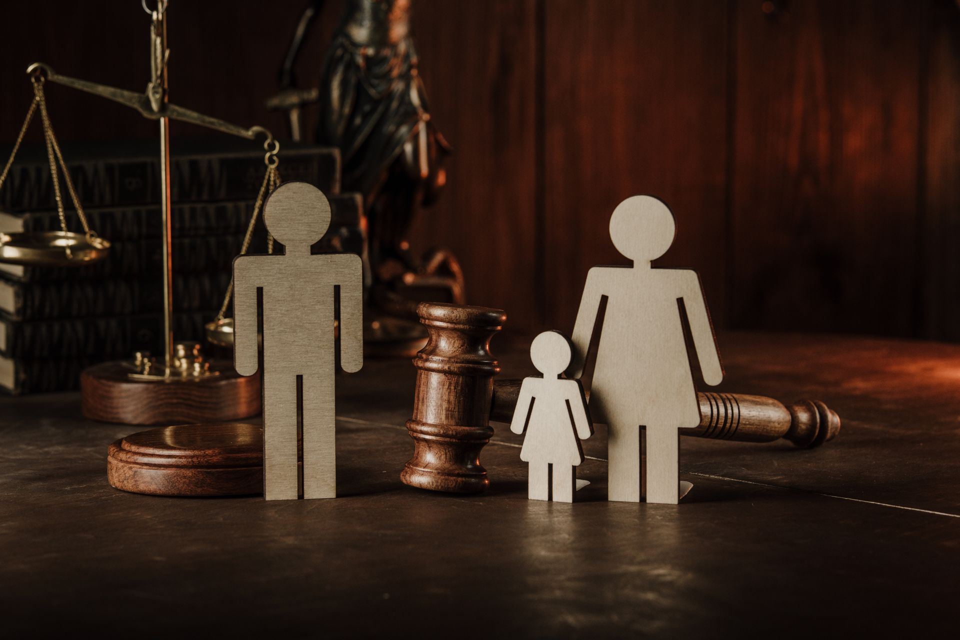 Family figurines in front of law scales, gavel, and books, symbolizing legal family matters.