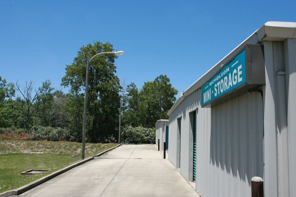 Storage units along a concrete path, under a blue sky, with trees in the background.
