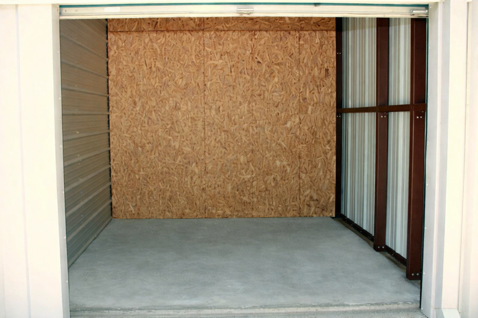 Storage unit with lawnmower and two pink flamingos.