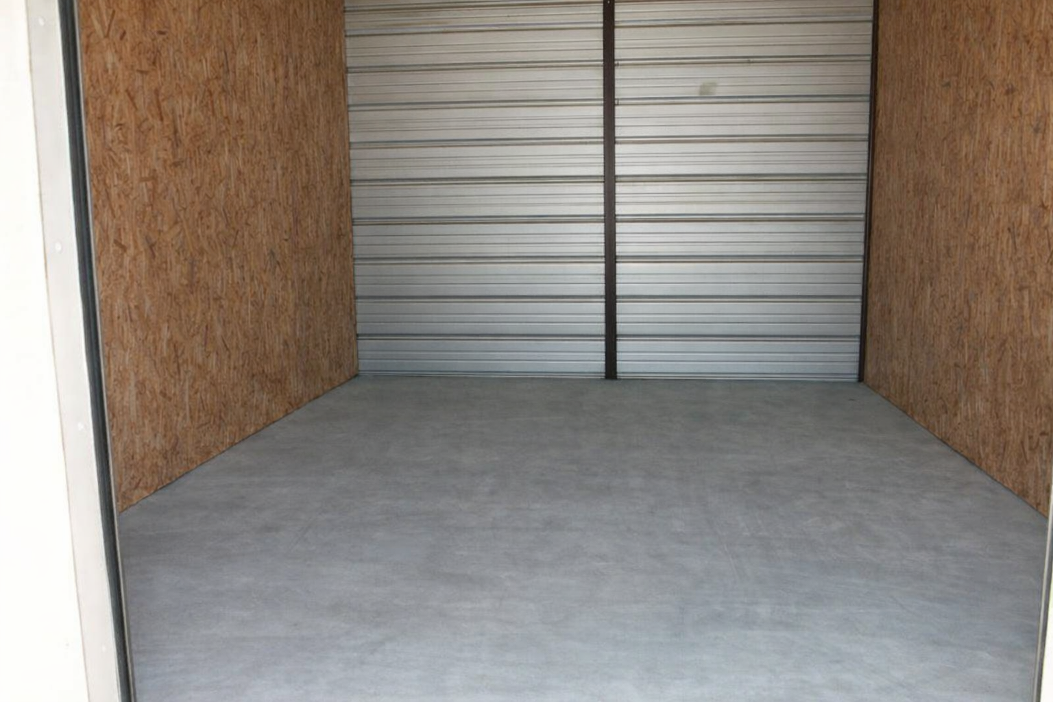 Storage unit with a lawnmower and two pink flamingo lawn ornaments.