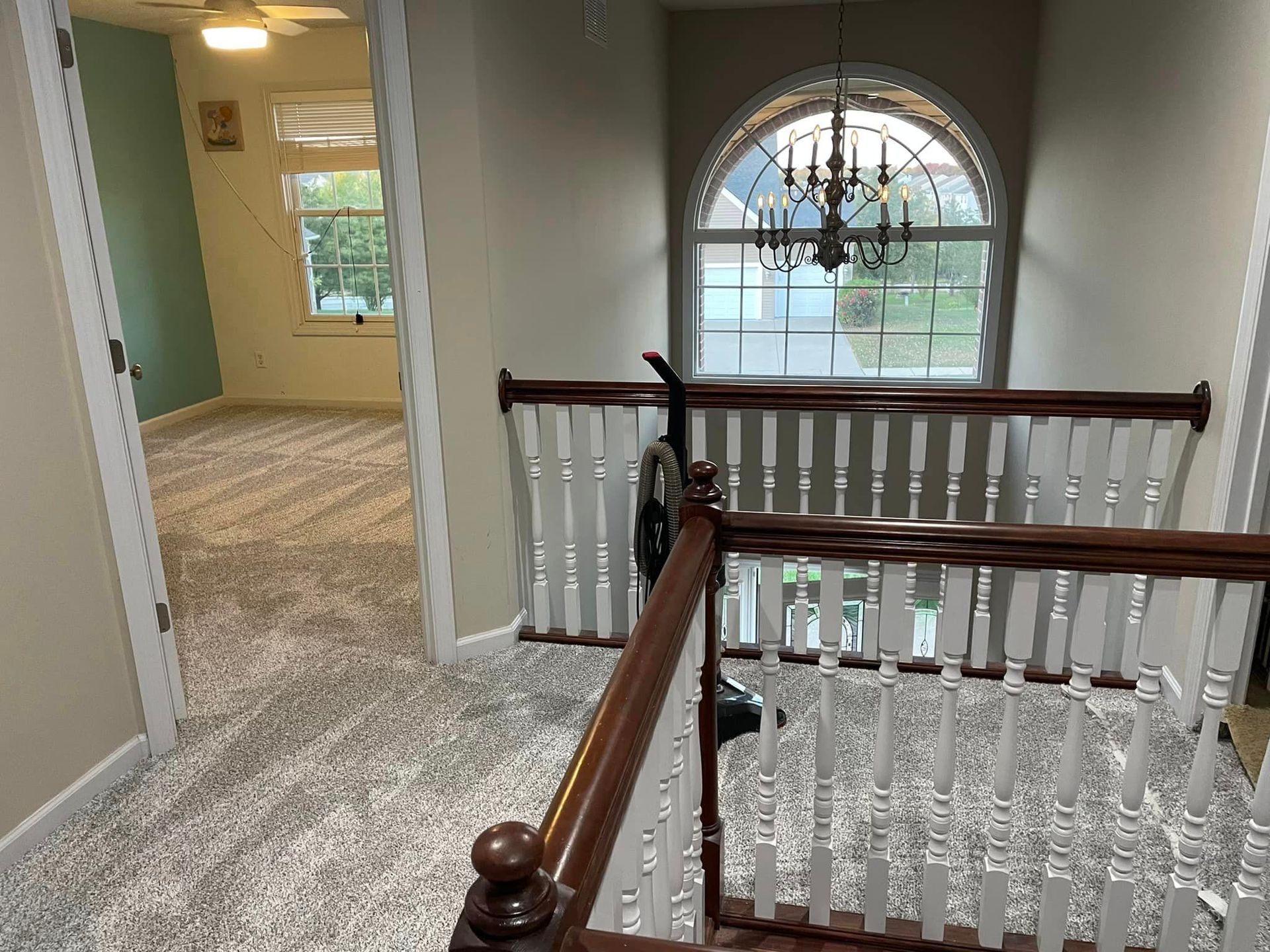 A staircase in a house with a wooden railing and a window.