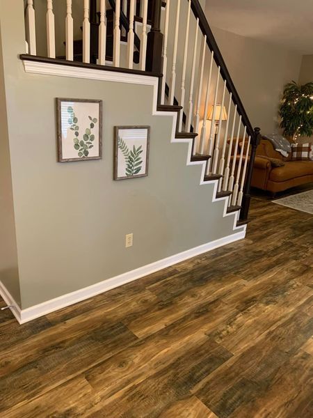 A living room with a staircase and a wooden floor.