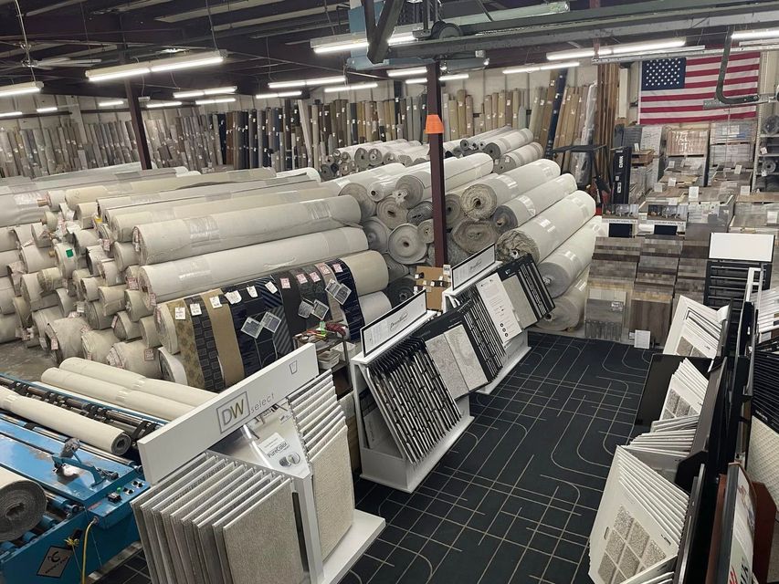 Industrial warehouse with rows of large rolls and machinery, with an American flag in the background