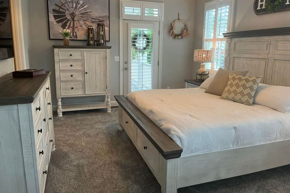 Cozy bedroom with gray bed, white dresser, and light wood furniture beside a glass door