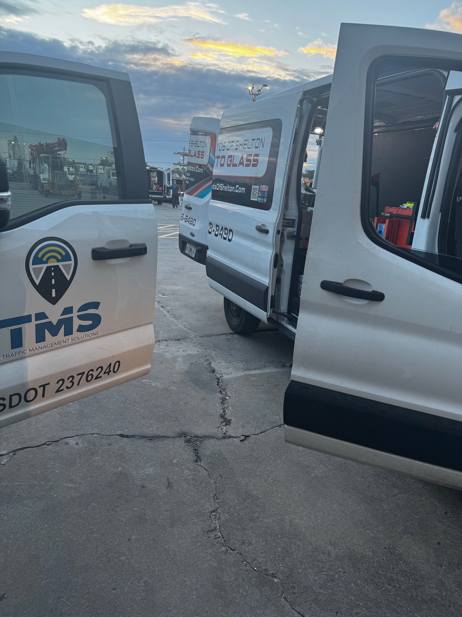 Commercial Fleet Glass Replacement: Open white utility van with TM5 logo parked on a street at dusk, side and rear doors open.