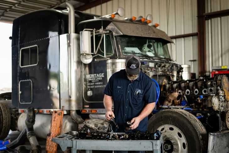 Mechanic using a tool to work on a car’s transmission under the vehicle