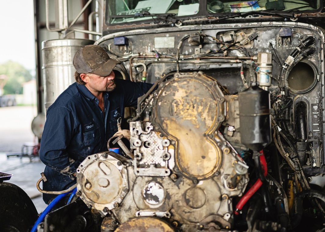 Mechanic using a tool to work on a car’s transmission under the vehicle