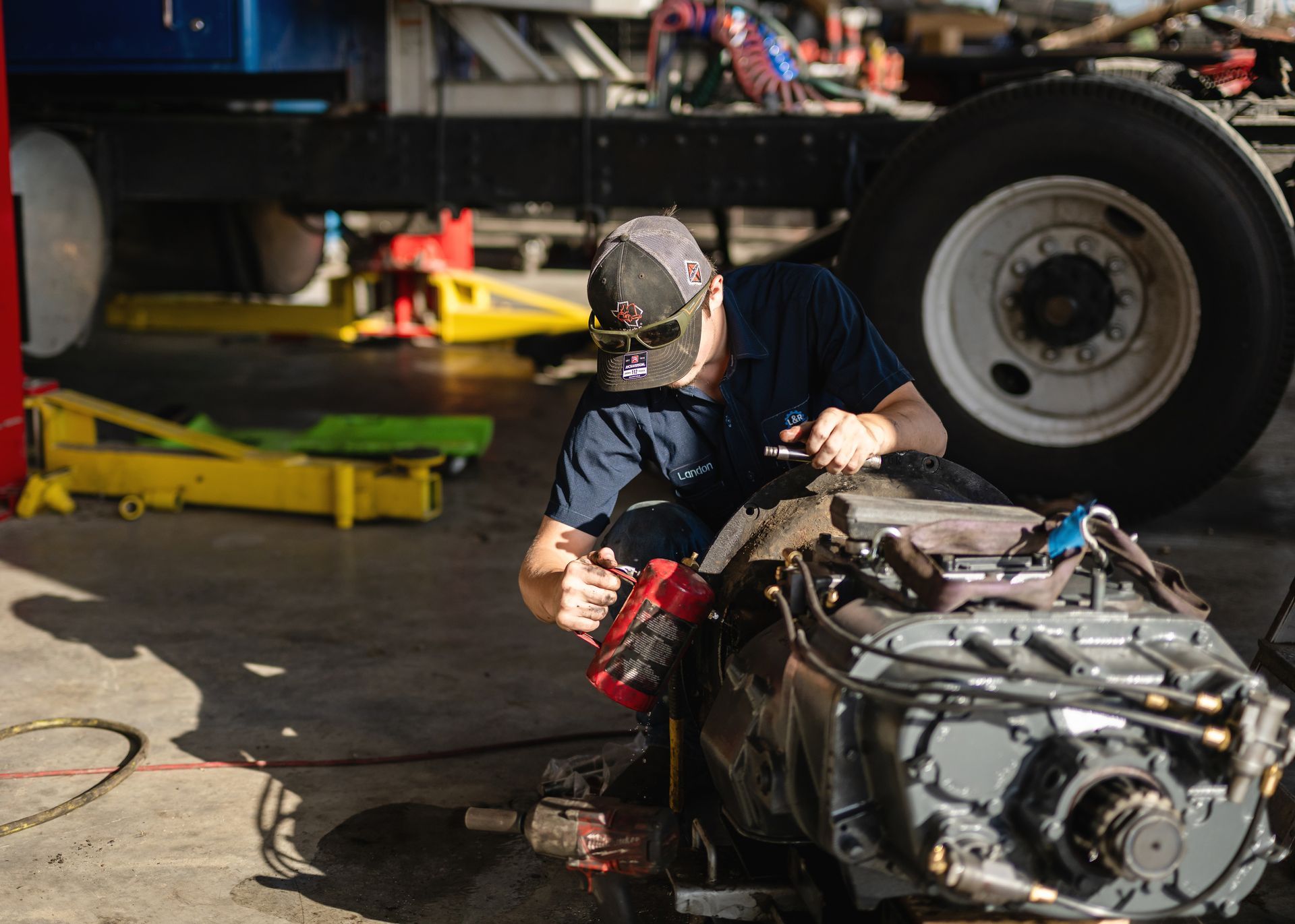 Hands inspecting a rusty turbocharger on a workbench in an auto repair shop