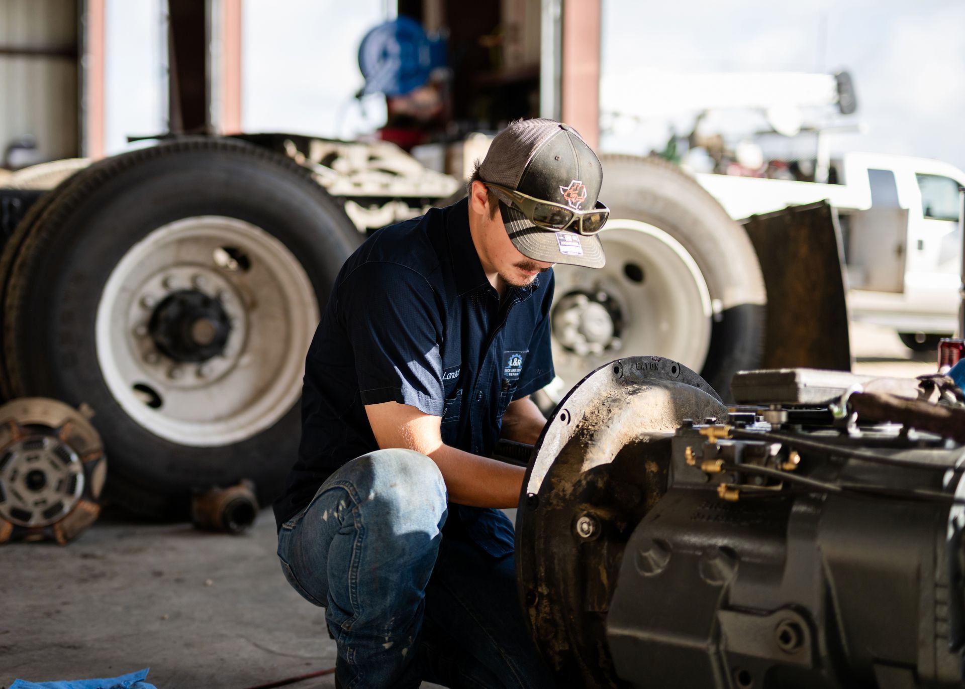 Gloved mechanic inspecting a car brake rotor and wheel hub with a red tool.