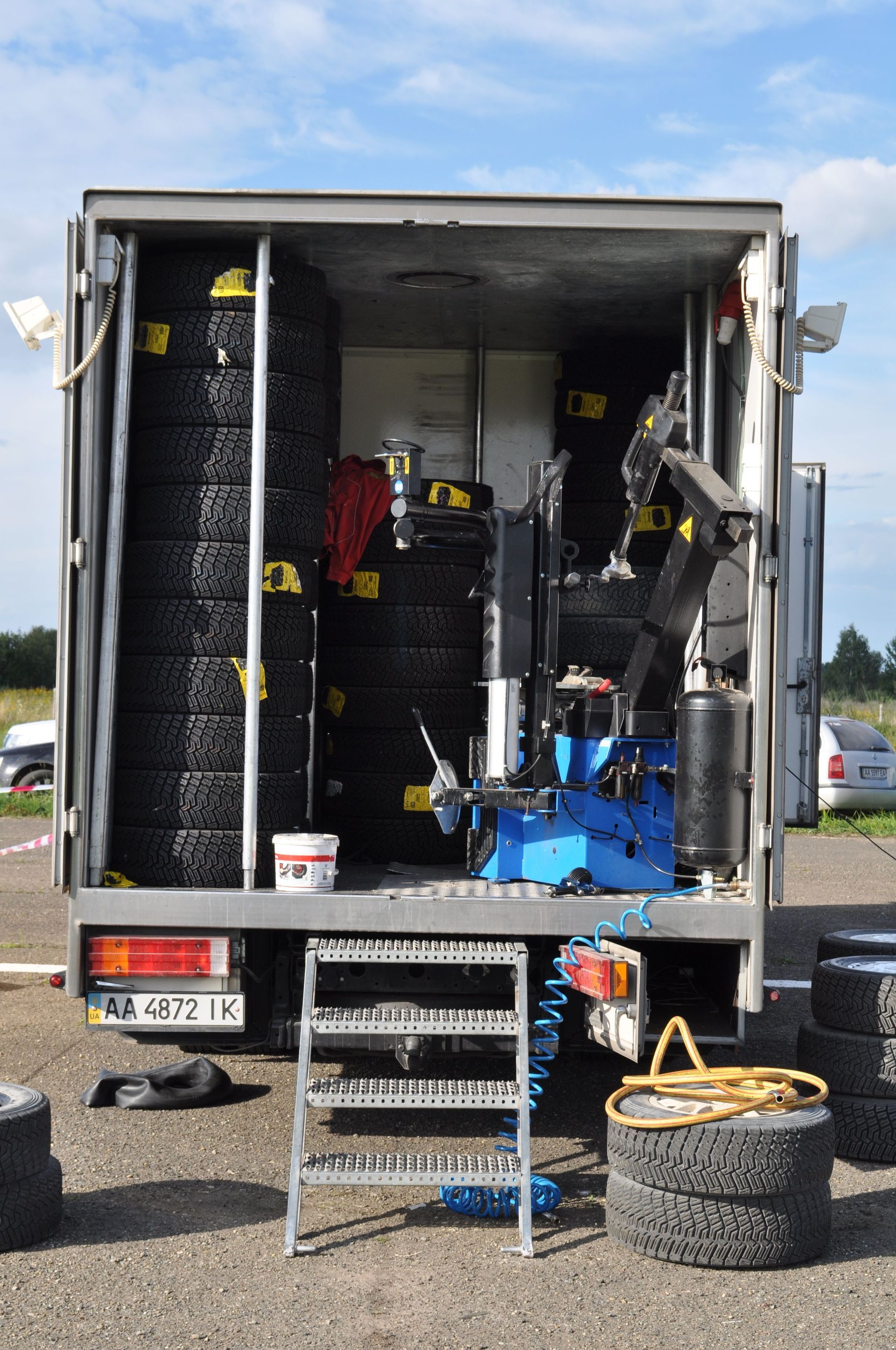 Open trailer packed with tires, tools, and equipment at a racetrack pit area