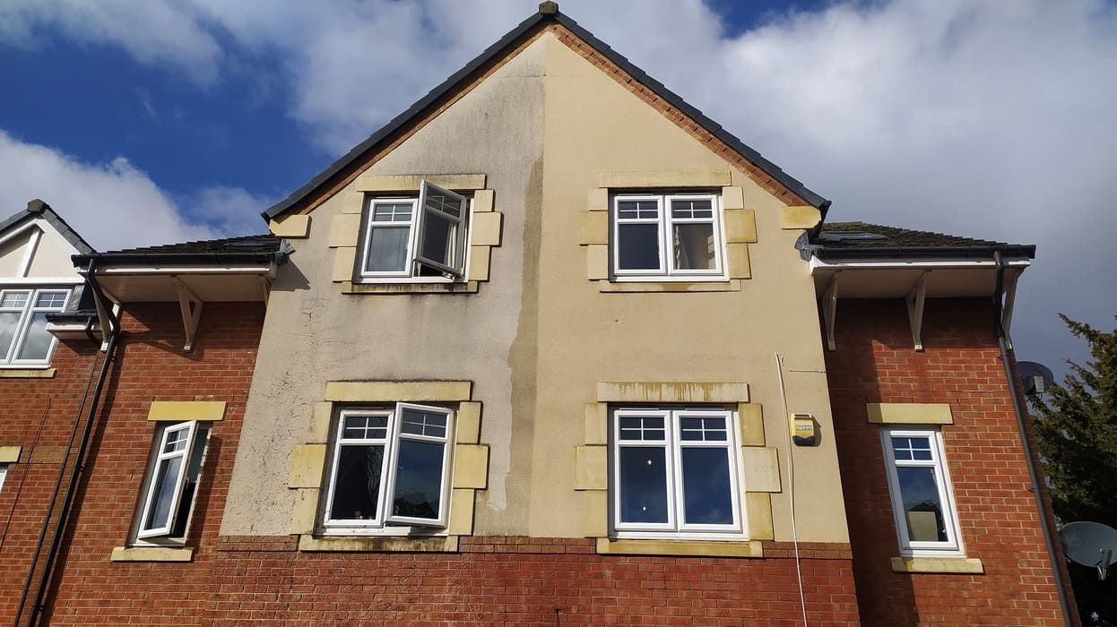 Semi detached house with dirty render getting cleaned and soft washed on a sunny day.