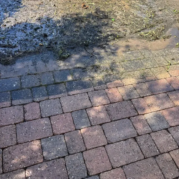 Block paving during pressure washing showing dirt and moss removal