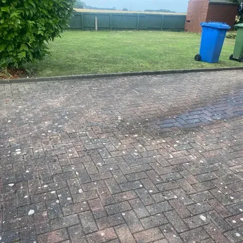 Weathered block paving with dirt and organic growth before professional cleaning