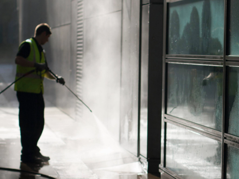 Pressure washing exterior of building.