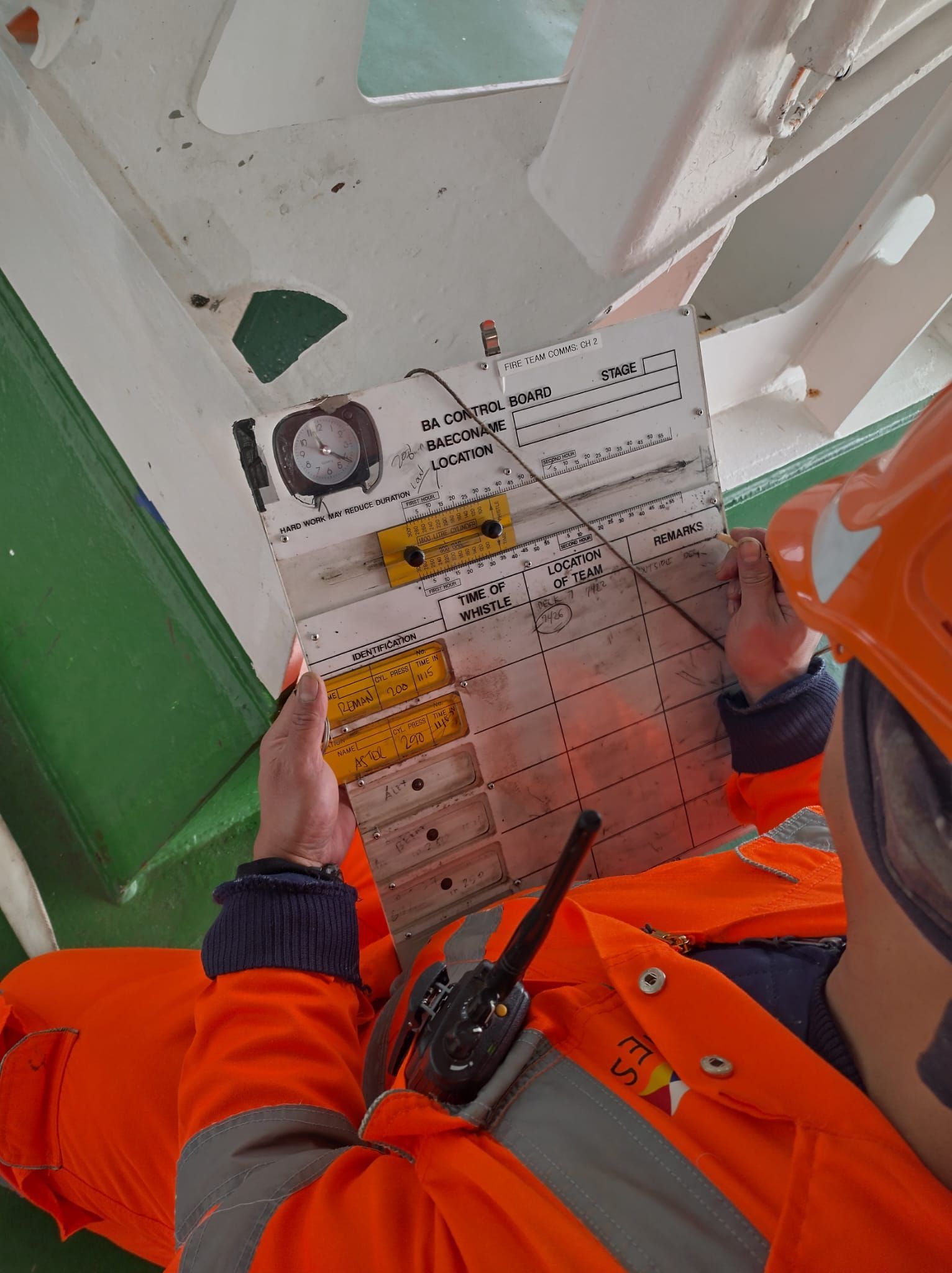 Persoon in oranje veiligheidsuitrusting inspecteert een ademlucht bord.