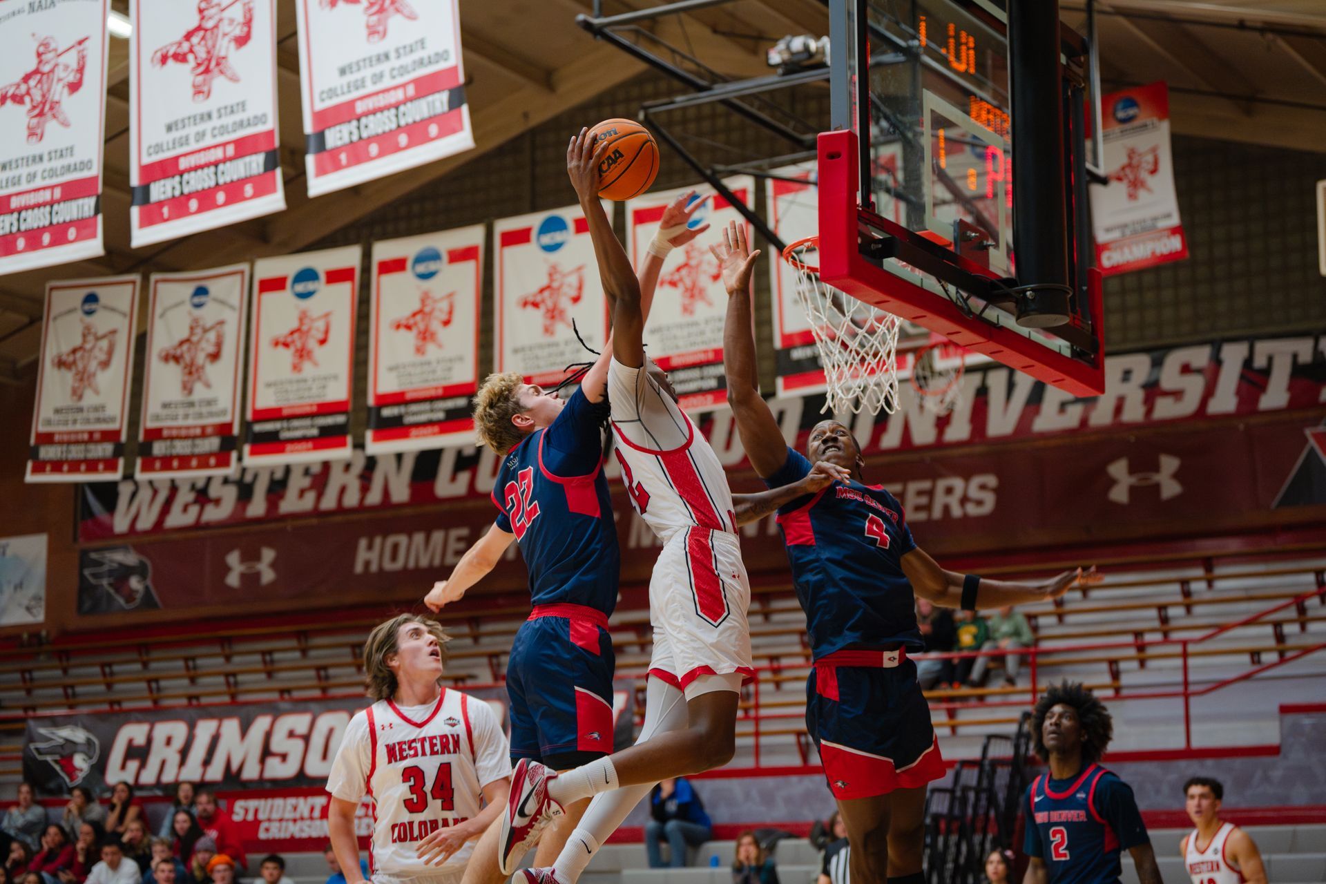 Basketball player shoots over two defenders in a Western Kentucky University gym