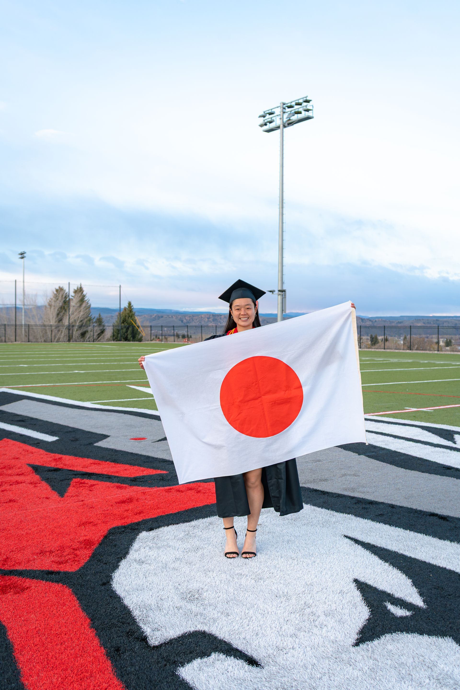 Person holding a Japanese flag on a football field at midfield logo
