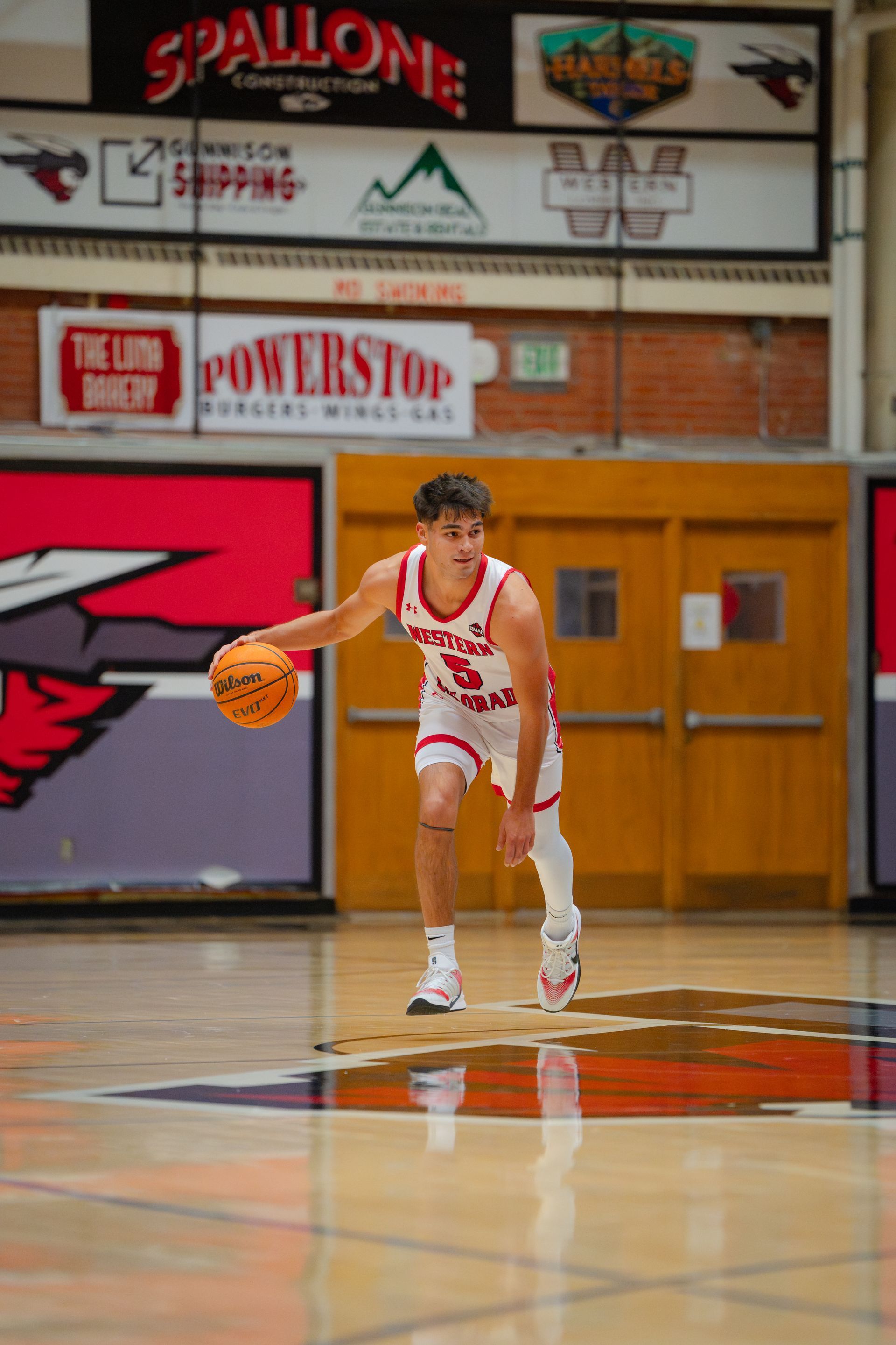 Basketball player dribbling on an indoor court near center court logo