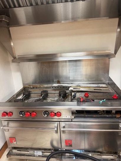 Commercial stainless-steel gas stovetop with six burners and a large hood in a kitchen