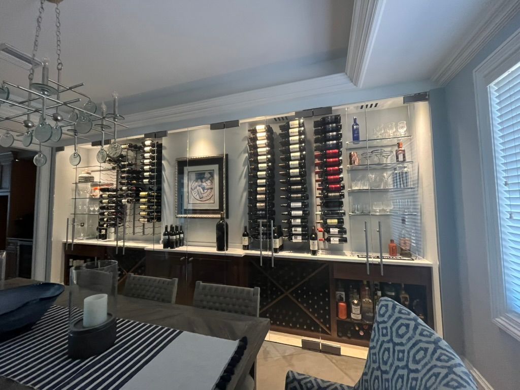 A dining room features a wall-mounted wine rack display with LED lighting, shelving, and storage cabinets beneath.