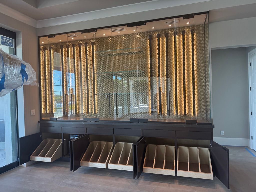 A modern wine cellar with floor-to-ceiling glass racks, warm accent lighting, and lower cabinetry with slanted wood shelves.