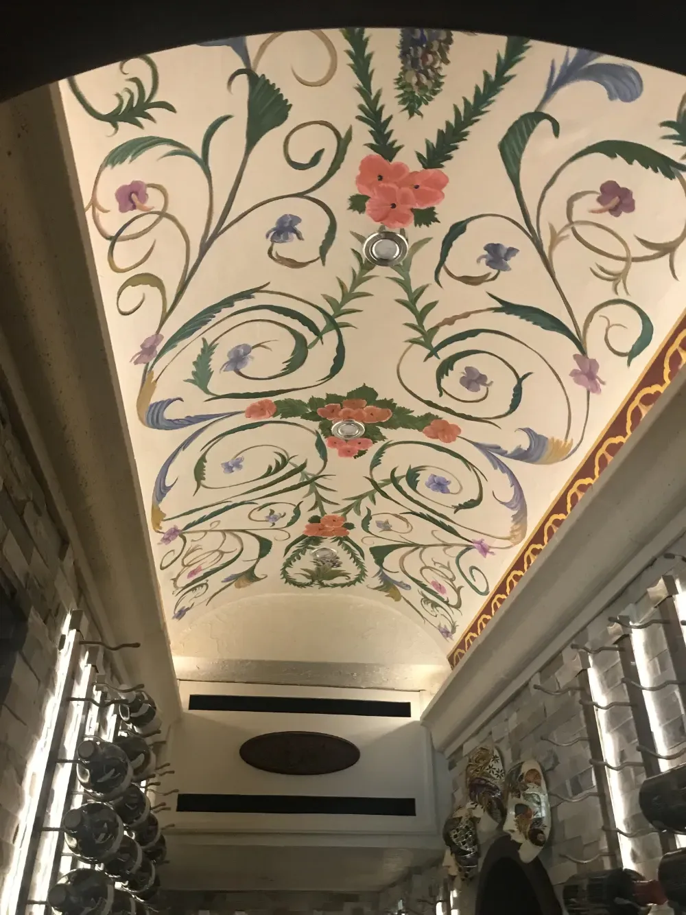 An arched ceiling features a mural with painted pink flowers and green foliage vines on a white background.
