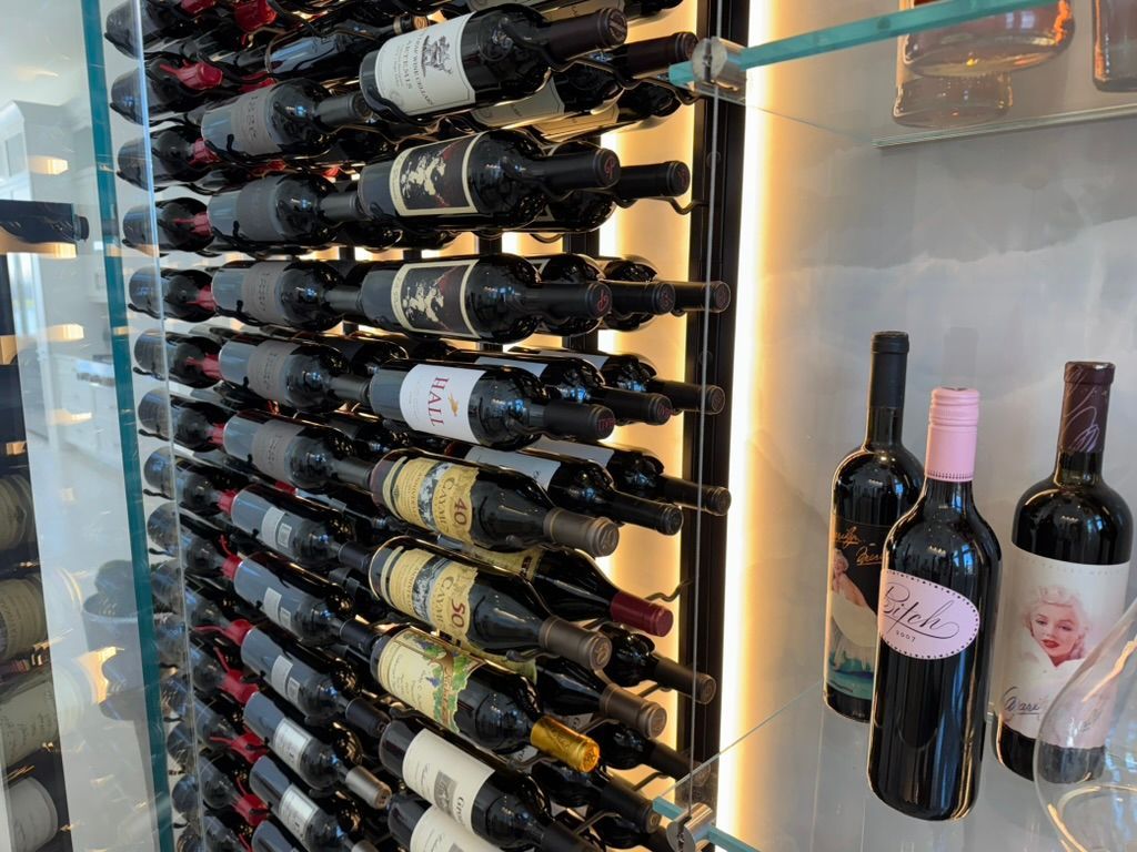 A wine cellar featuring a floor-to-ceiling rack filled with bottles, with two standing bottles displayed in front.