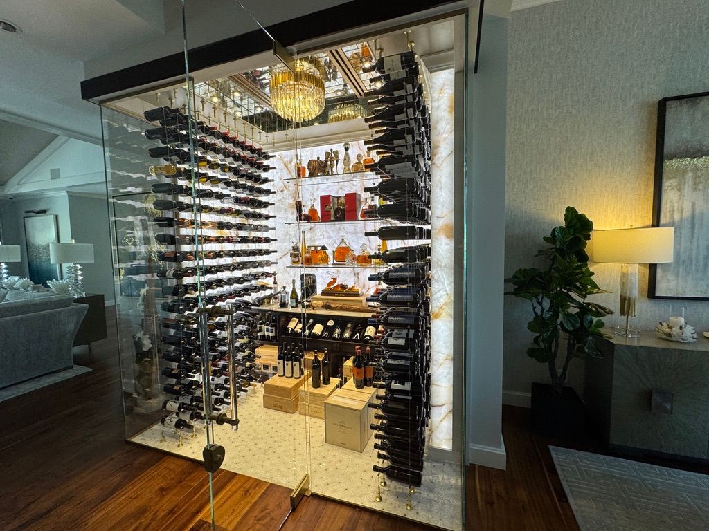 A modern, glass-enclosed wine cellar with floor-to-ceiling metal racks, LED-lit stone walls, and wooden crates.