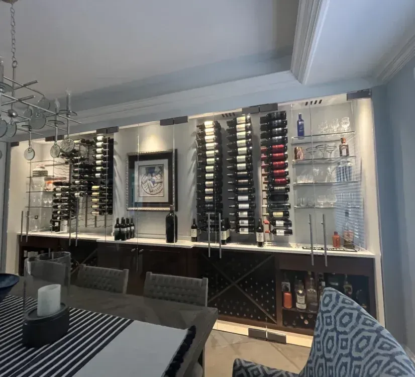 A dining room wall featuring a built-in wine rack display with LED lighting, cabinets, and a framed art piece.