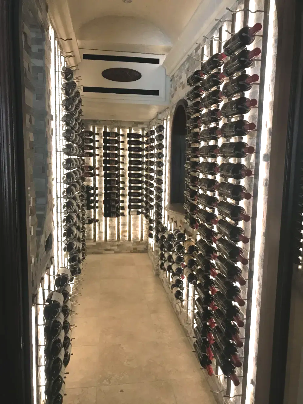 Wine cellar with bottles displayed in racks, lit by vertical lights.