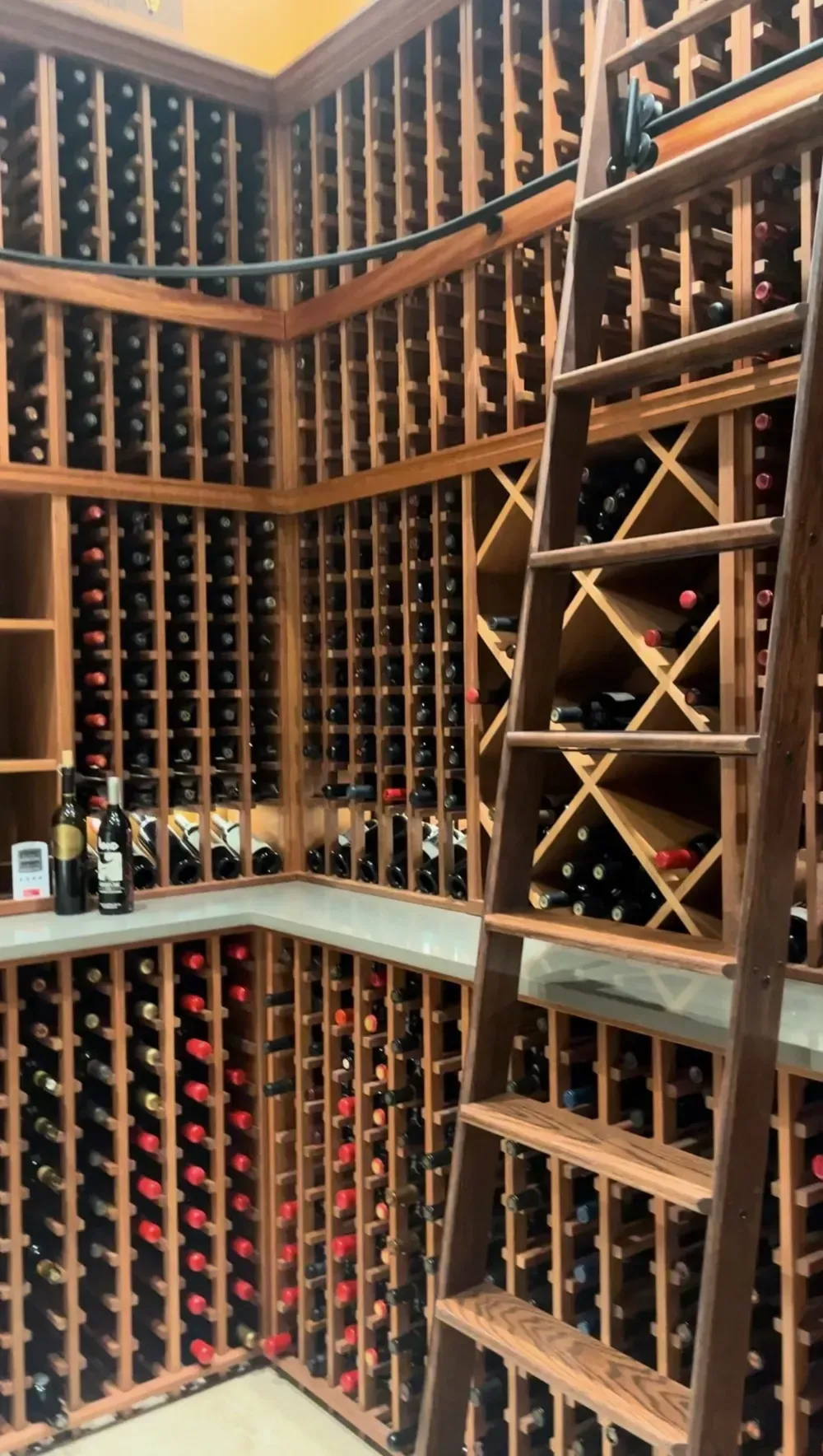 Wine cellar with wooden racks filled with bottles and a ladder.